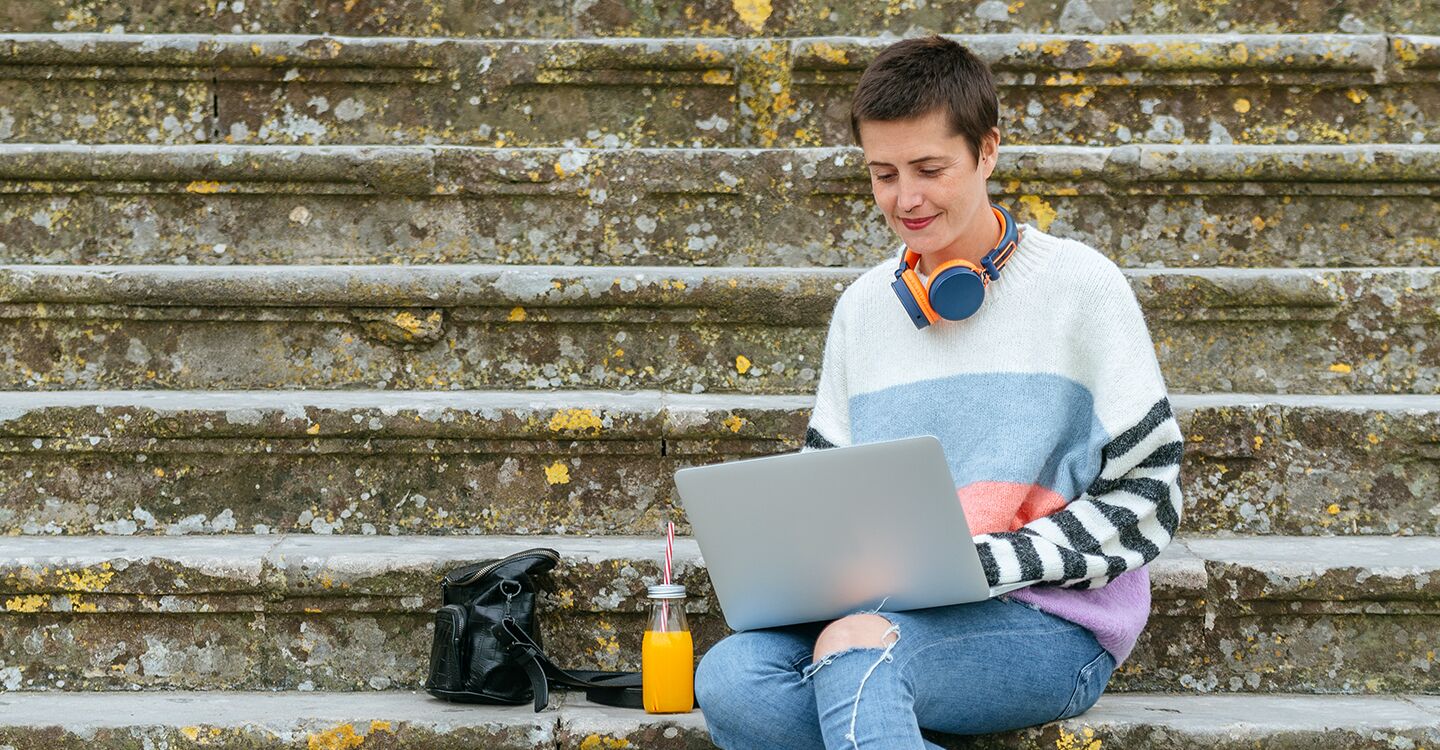 Frau nutz Notebook auf Treppe draußen