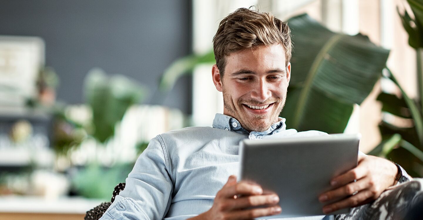 Mann in Büro am Tablet lächelnd