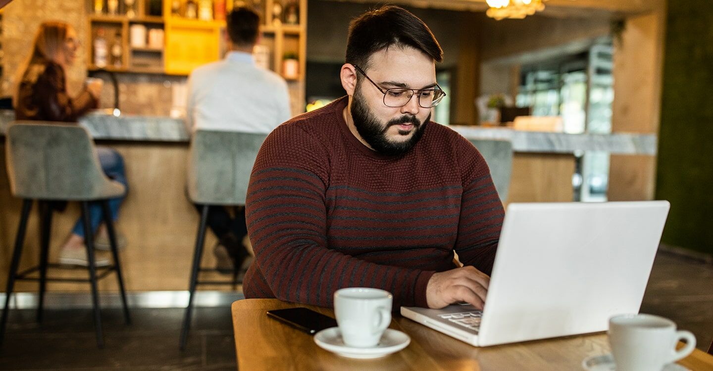 Mann arbeitet in einem Café am Notebook