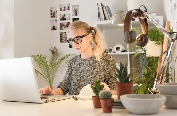 Frau sitzt vor Laptop, daneben technisches Equipment zum Lernen