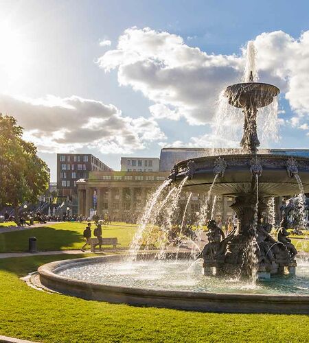 Beliebter Platz mit Springbrunnen vor dem Königsbau in Stuttgart bei Sonnenschein, Deutschland.