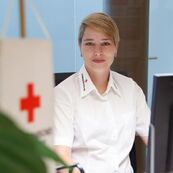 Portrait Angelika Kellner an Schreibtisch mit Rotes-Kreuz-Symbol im Vordergrund