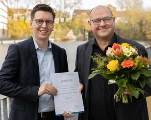 Prof. Dr. Lars Binckebanck überreicht Prof. Dr. Florian Oldenburg-Tietjen die Ernennungsurkunde und einen Blumenstrauß.
