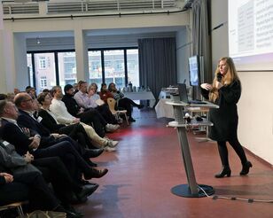 Speakerin steht vor Publikum und referiert