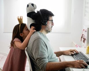 Kind beobachtet Vater wie er am Laptop arbeitet