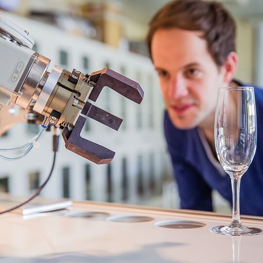 Maschinenbau-Student mit Roboter und Sektglas