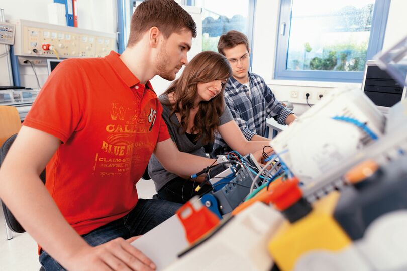 Drei jungen Menschen arbeiten an technischen Apparaturen