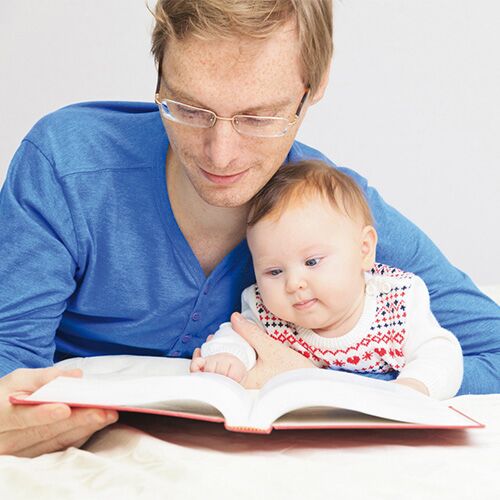 Mann blättert mit Baby in einem Buch