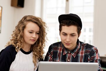 zwei junge Menschen sitzen vor einem Laptop