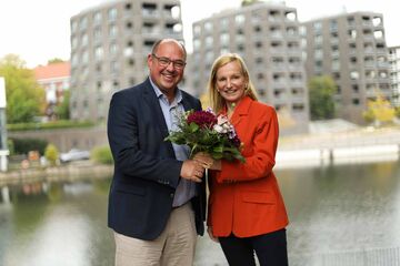 Prof. Dr. Lars Binckebanck überreicht Blumenstrauß an Prof. Dr. Irina Kummert am Osterbekkanal.