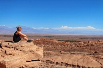 Bettina Mandel sitzt in der Wüste auf einem Felsen und schaut in die Weite