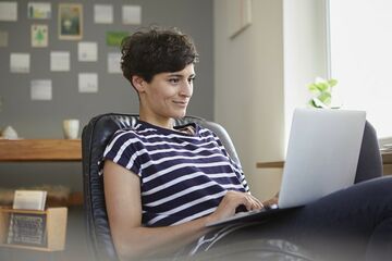 Junge Frau sitzt mit Laptop an einem Tisch