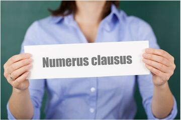 Symboldbild einer Dame, die ein Schild mit den Worten Numerus Clausus hochhält.
